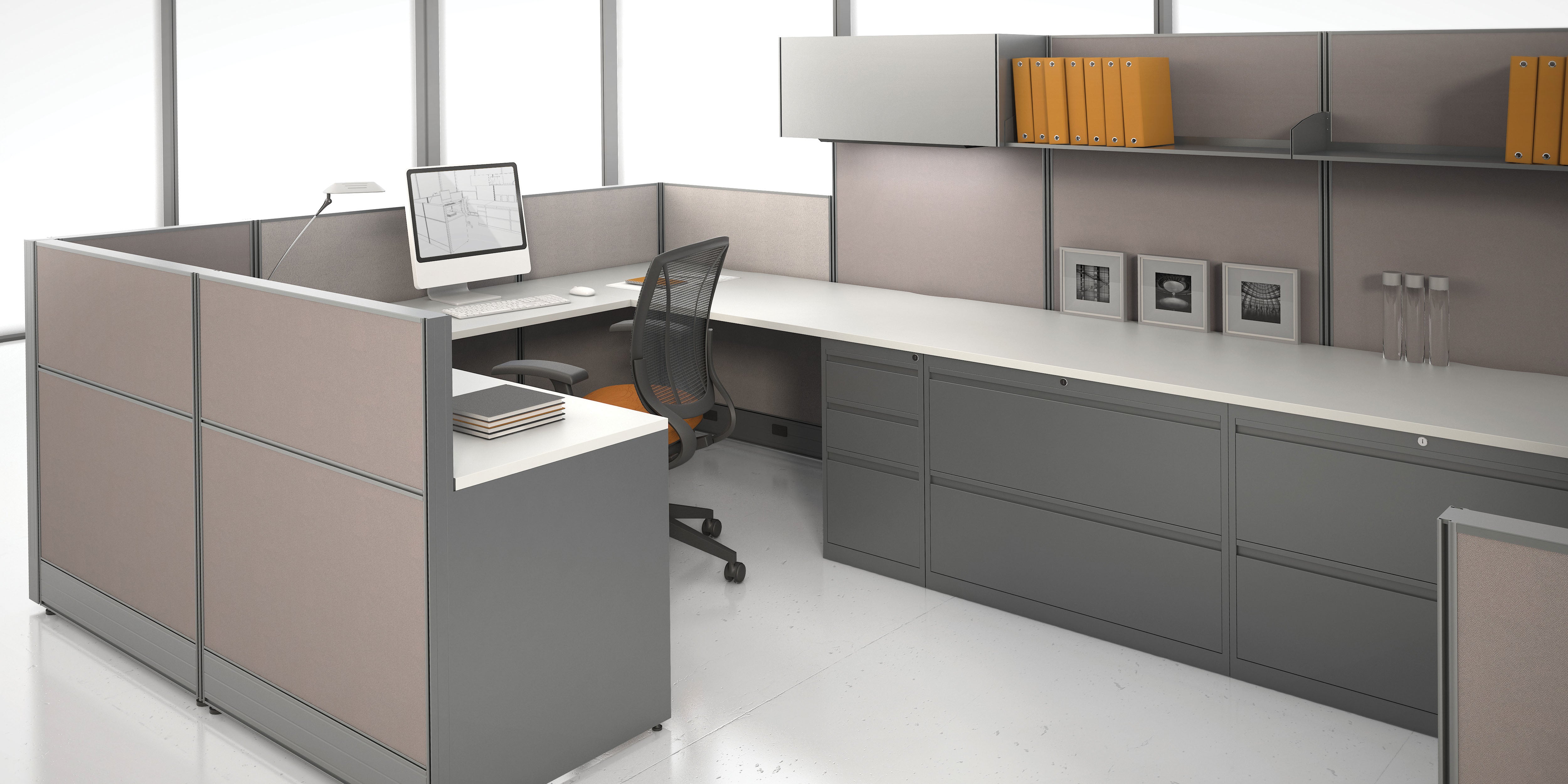 Modern office desk setup with computer and books in a bright room.
