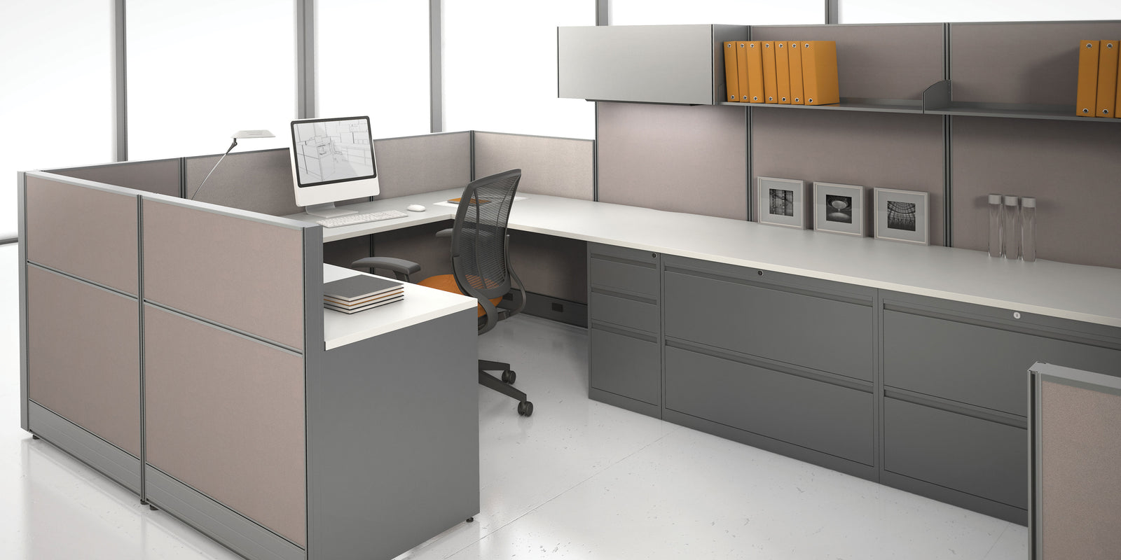Modern office desk setup with computer and books in a bright room.