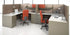 Modern office cubicles with orange chairs and white desks.