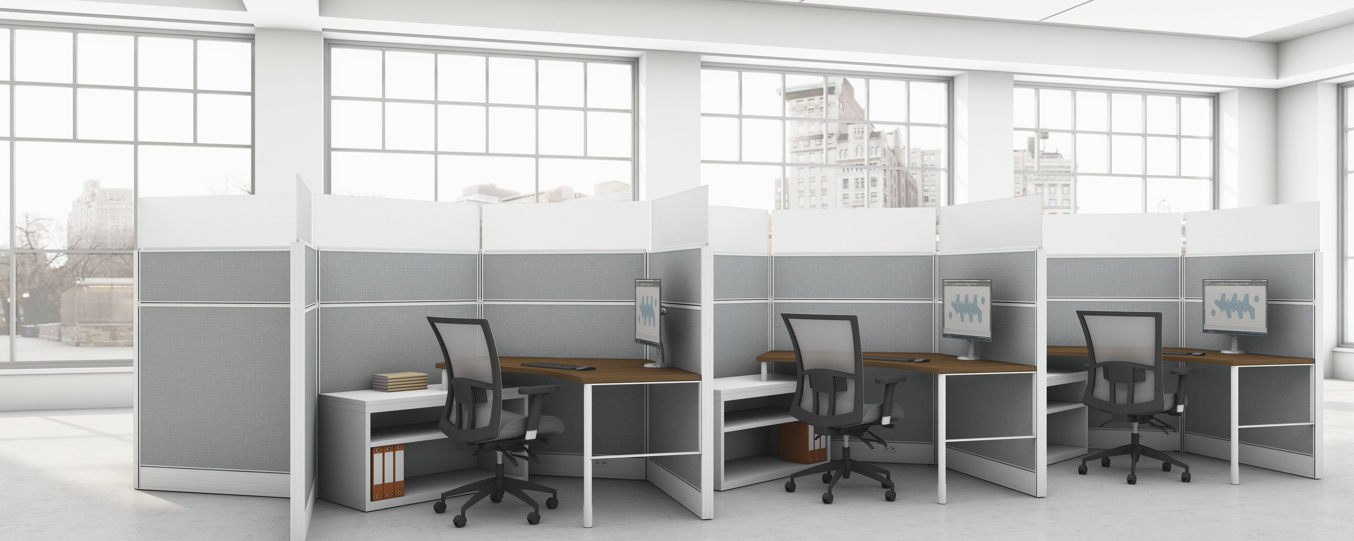 Modern office with cubicles and desks in a bright room with large windows.