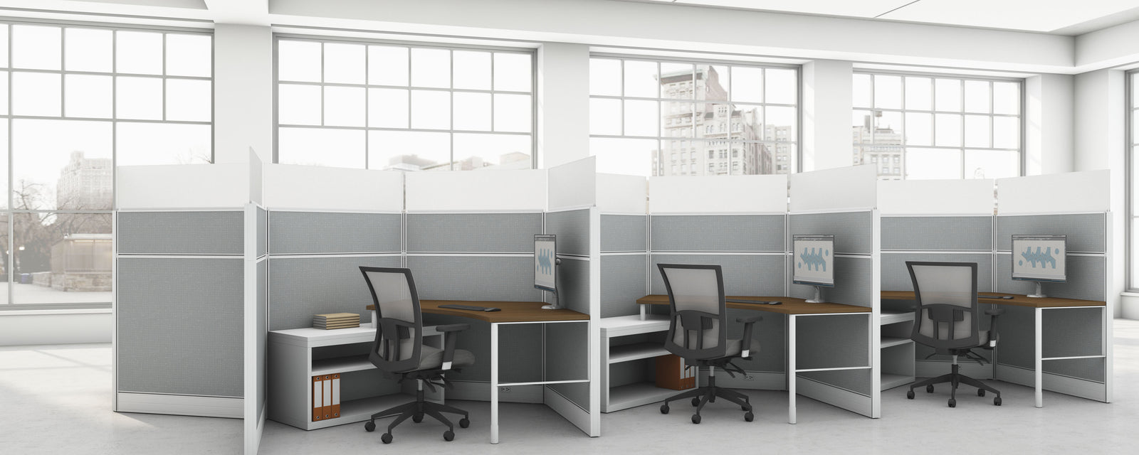 Modern office with cubicles and desks in a bright room with large windows.